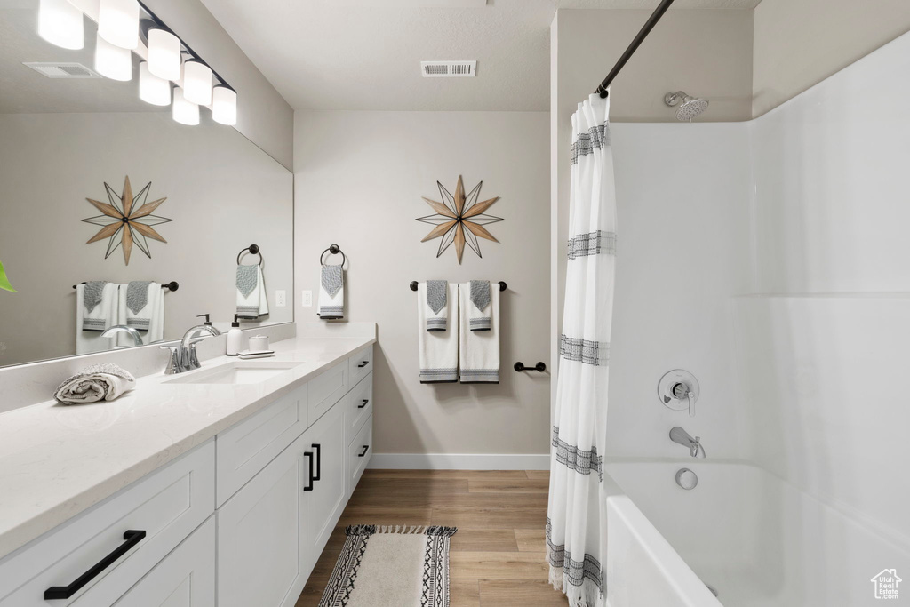 Bathroom with shower / bath combination with curtain, hardwood / wood-style flooring, and vanity