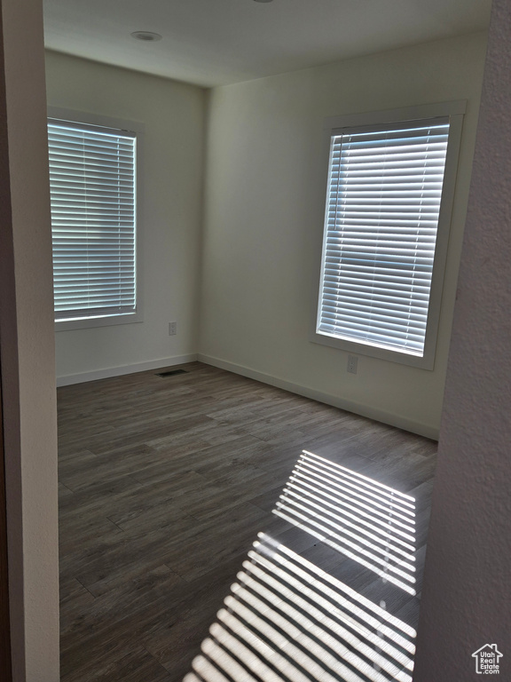 Empty room featuring dark hardwood / wood-style flooring