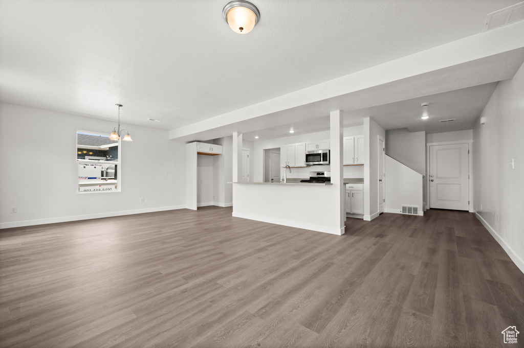 Unfurnished living room with a chandelier and dark wood-type flooring