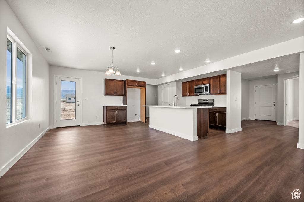 Kitchen featuring an island with sink, a textured ceiling, appliances with stainless steel finishes, and dark hardwood / wood-style floors