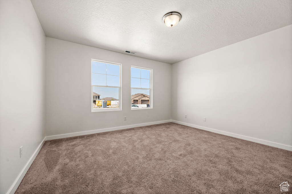 Carpeted empty room with a textured ceiling