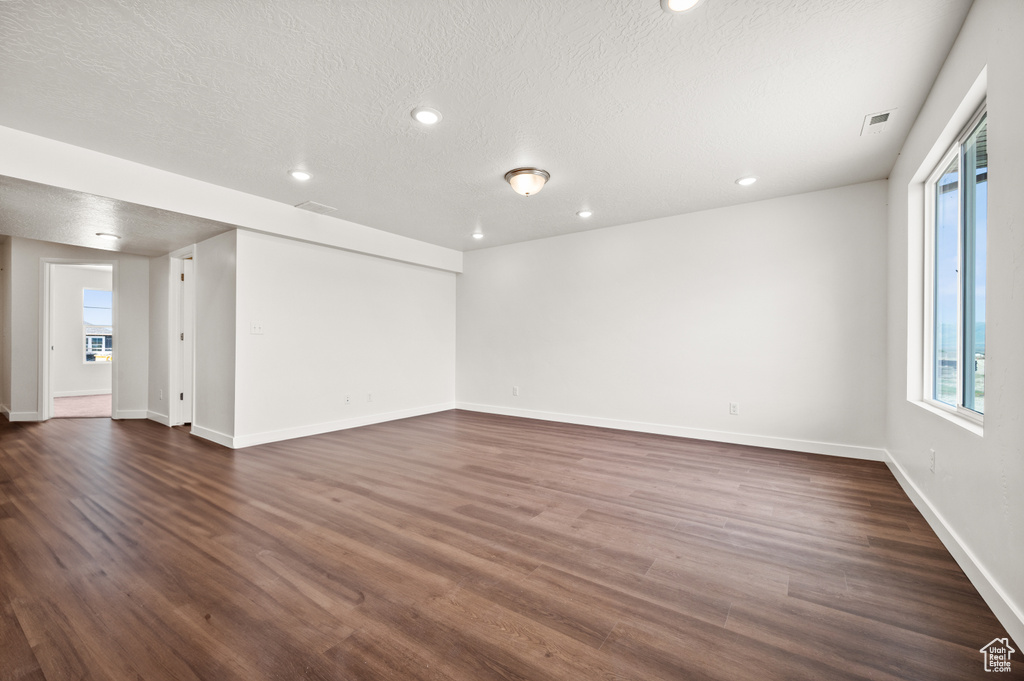 Unfurnished living room featuring a textured ceiling and dark hardwood / wood-style floors