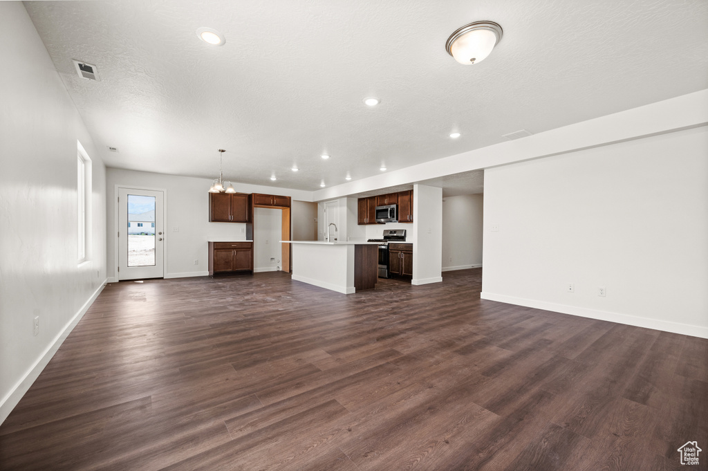 Unfurnished living room with a textured ceiling, sink, and dark hardwood / wood-style flooring