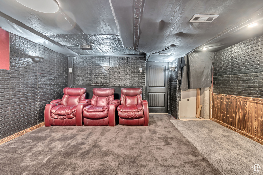 Cinema room with carpet, wooden walls, and brick wall