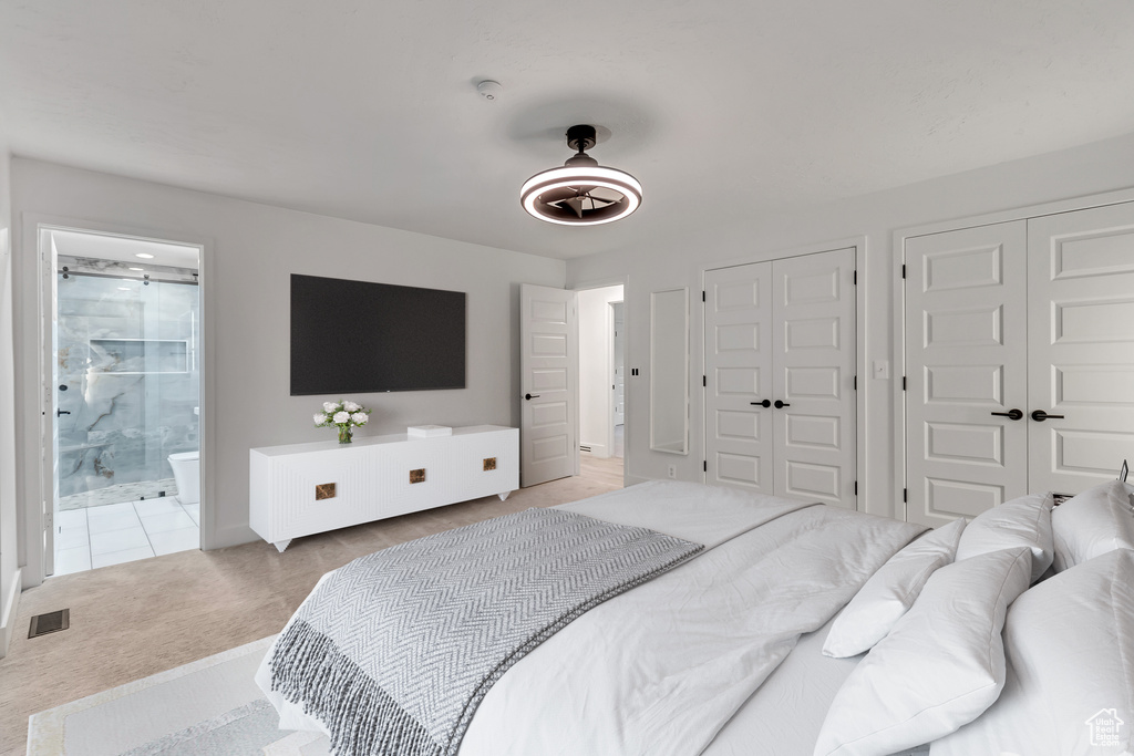 Bedroom featuring two closets, light carpet, ensuite bathroom, and ceiling fan