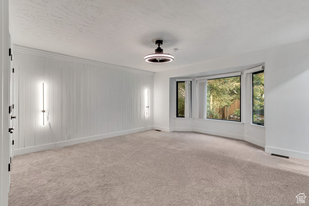 Empty room with a textured ceiling and light colored carpet