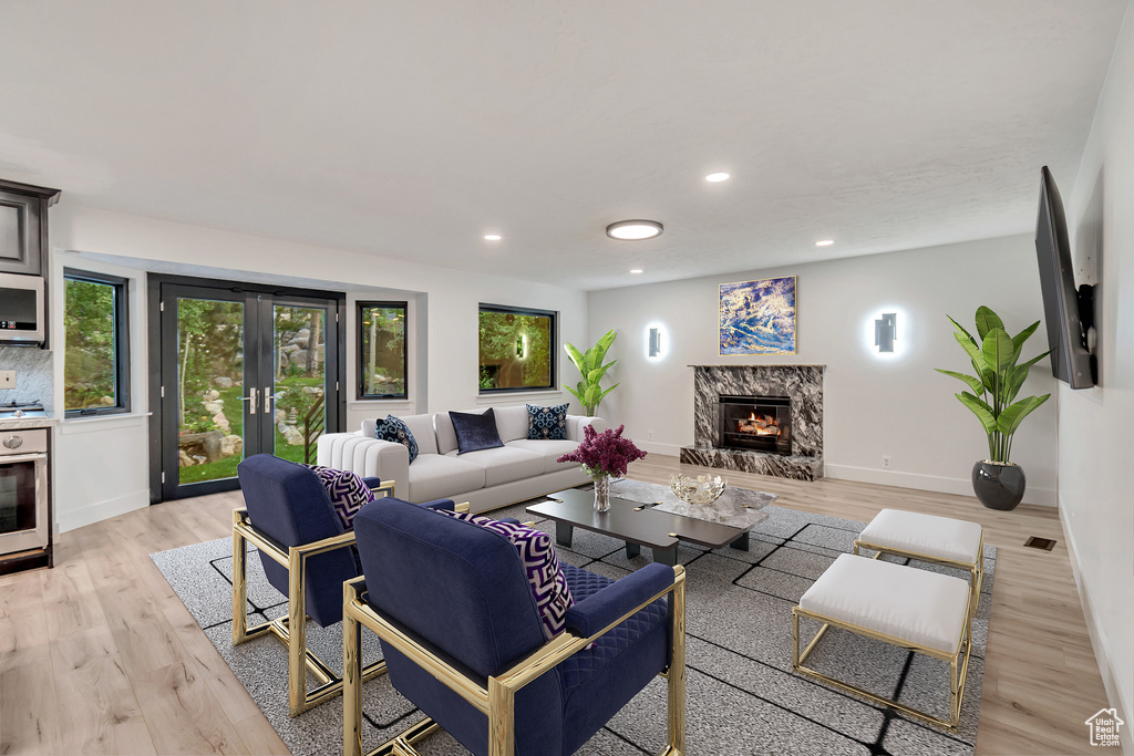 Living room featuring light wood-type flooring and a high end fireplace