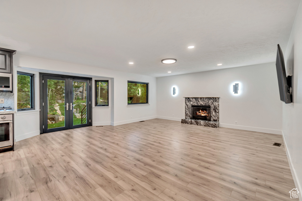 Unfurnished living room featuring a premium fireplace and light hardwood / wood-style floors