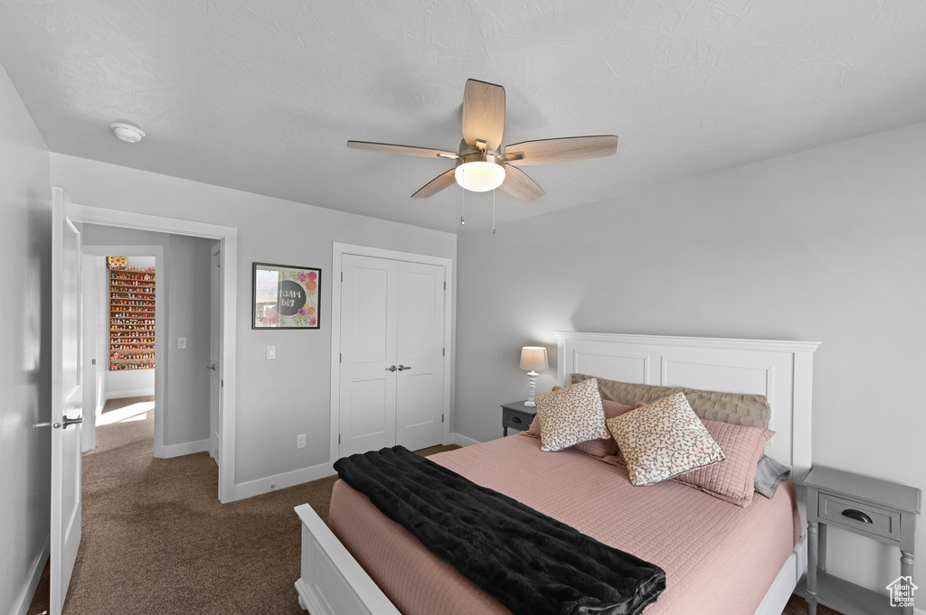 Carpeted bedroom with ceiling fan and a closet