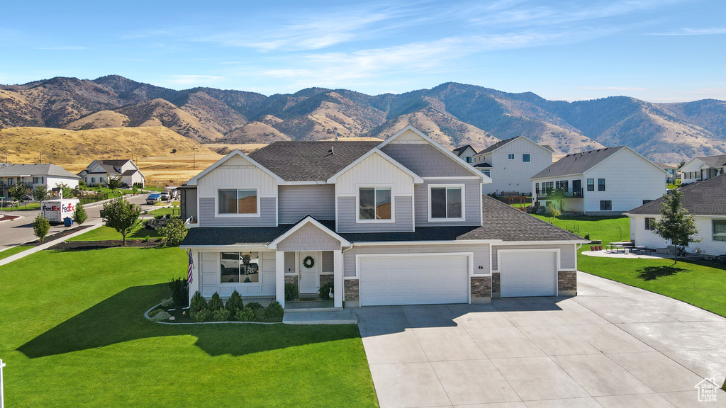 View of front facade featuring a mountain view, a garage, and a front lawn