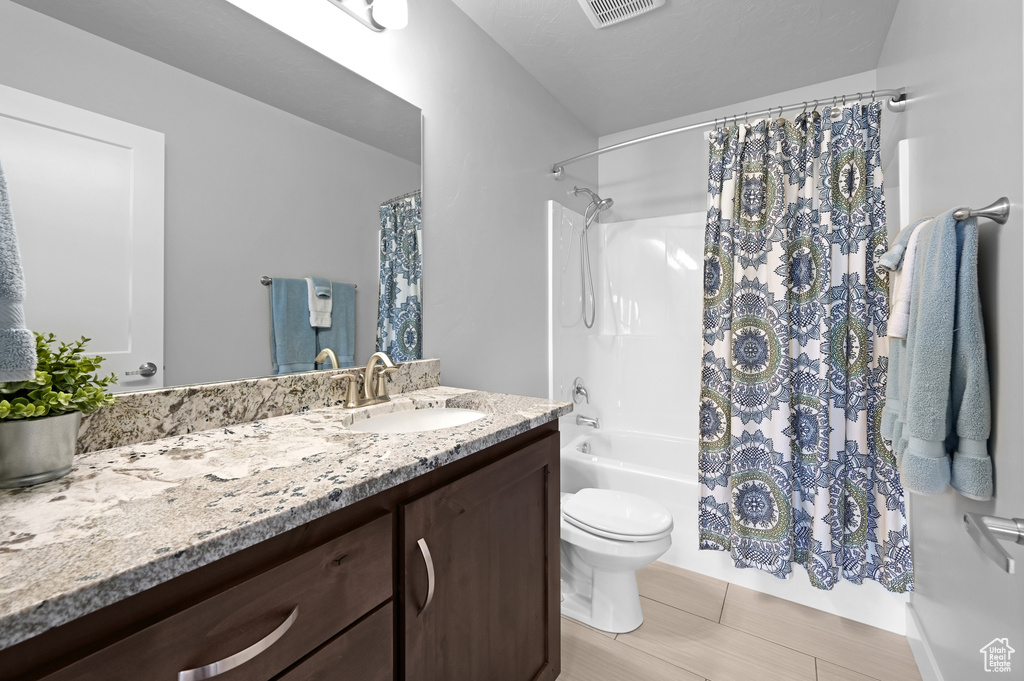 Full bathroom featuring wood-type flooring, vanity, shower / tub combo, and toilet