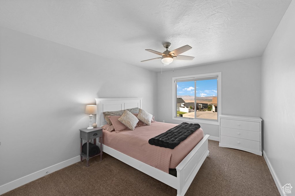 Bedroom featuring ceiling fan and dark colored carpet