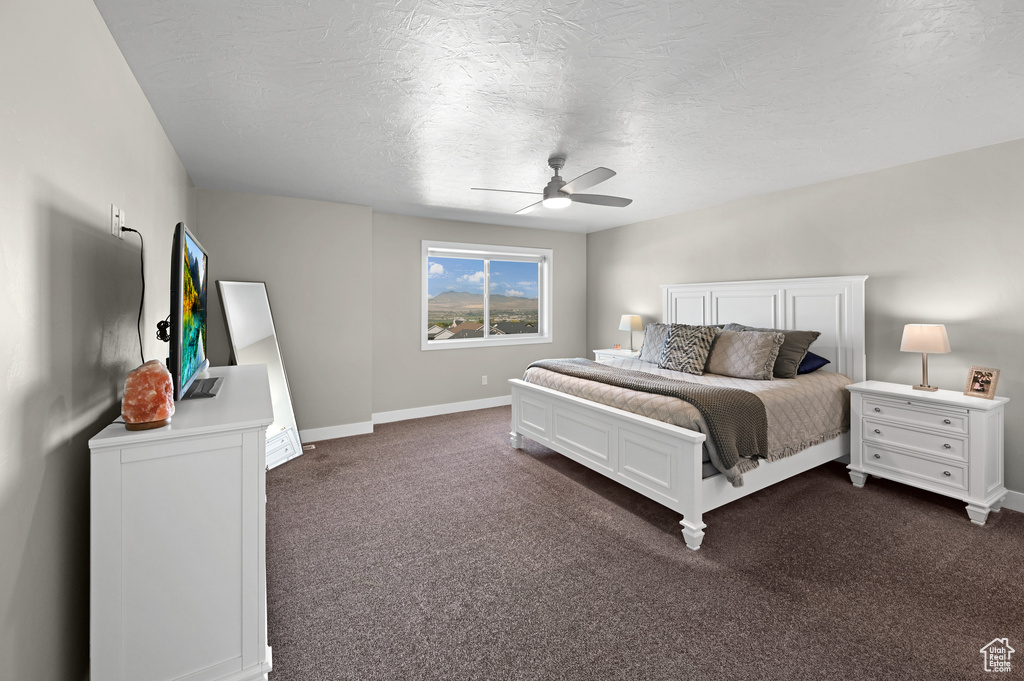 Carpeted bedroom featuring ceiling fan and a textured ceiling