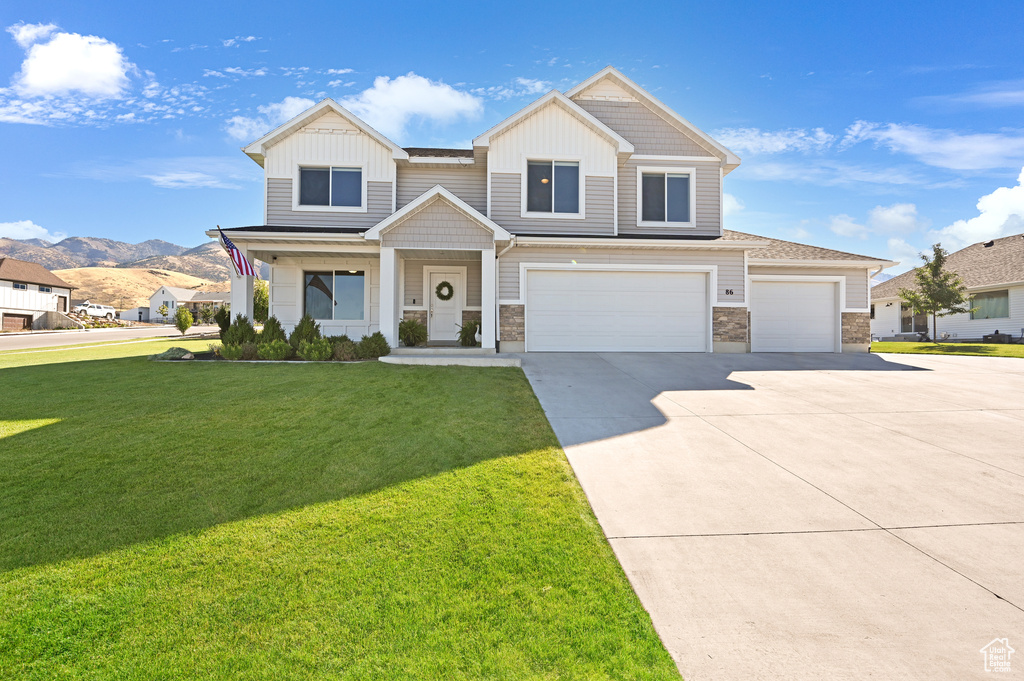 View of front of house with a garage, a front lawn, and a mountain view