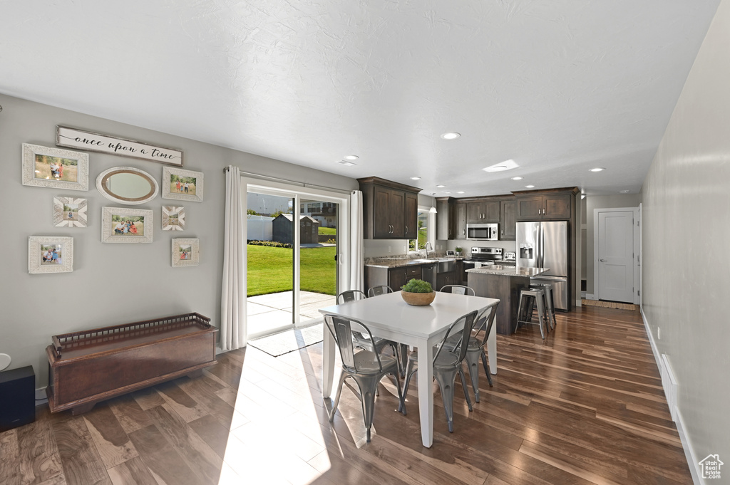 Dining space featuring sink and dark wood-type flooring