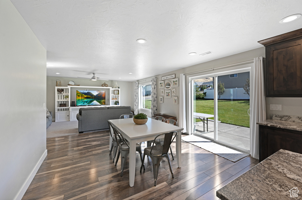 Dining space with ceiling fan, dark wood-type flooring, and a textured ceiling