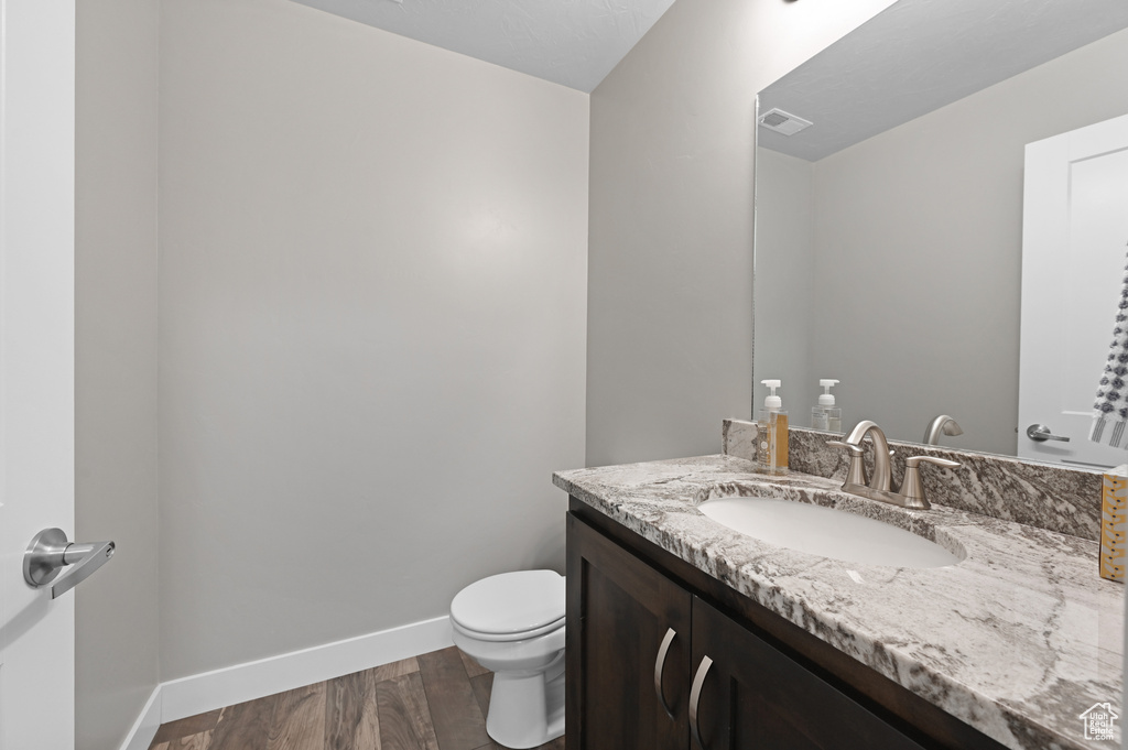 Bathroom featuring hardwood / wood-style floors, vanity, and toilet