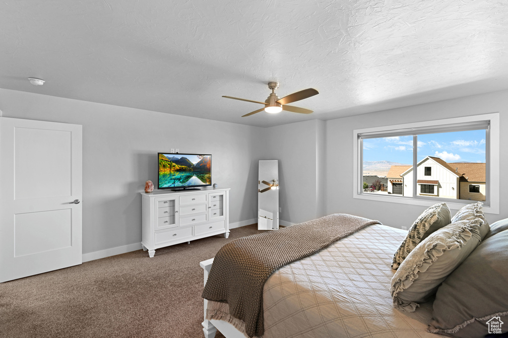 Carpeted bedroom featuring a textured ceiling and ceiling fan