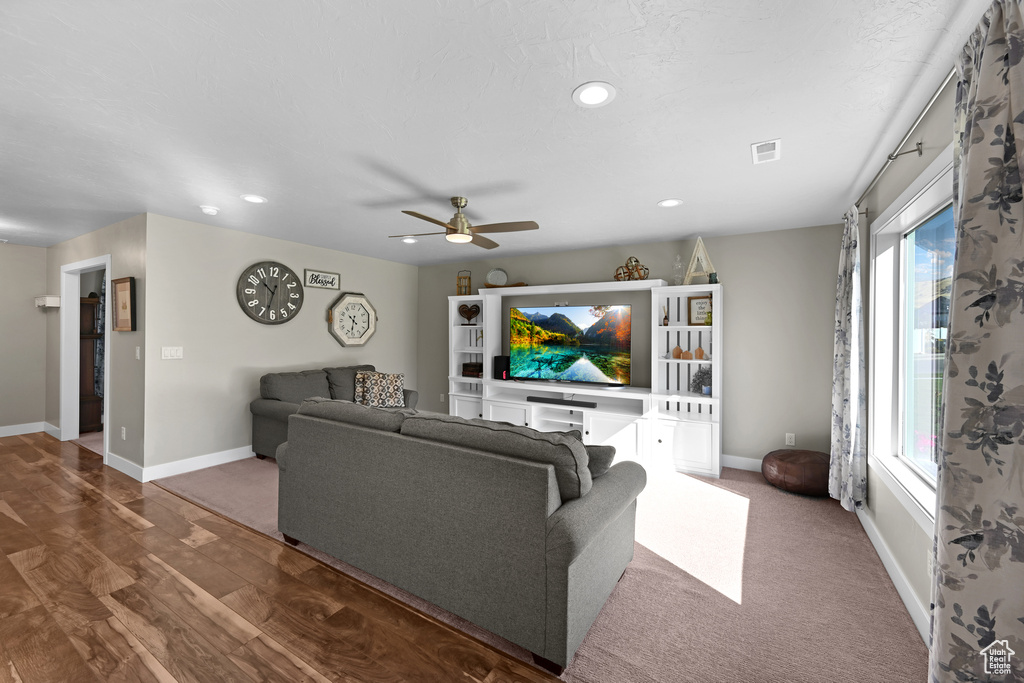 Living room with ceiling fan and hardwood / wood-style floors