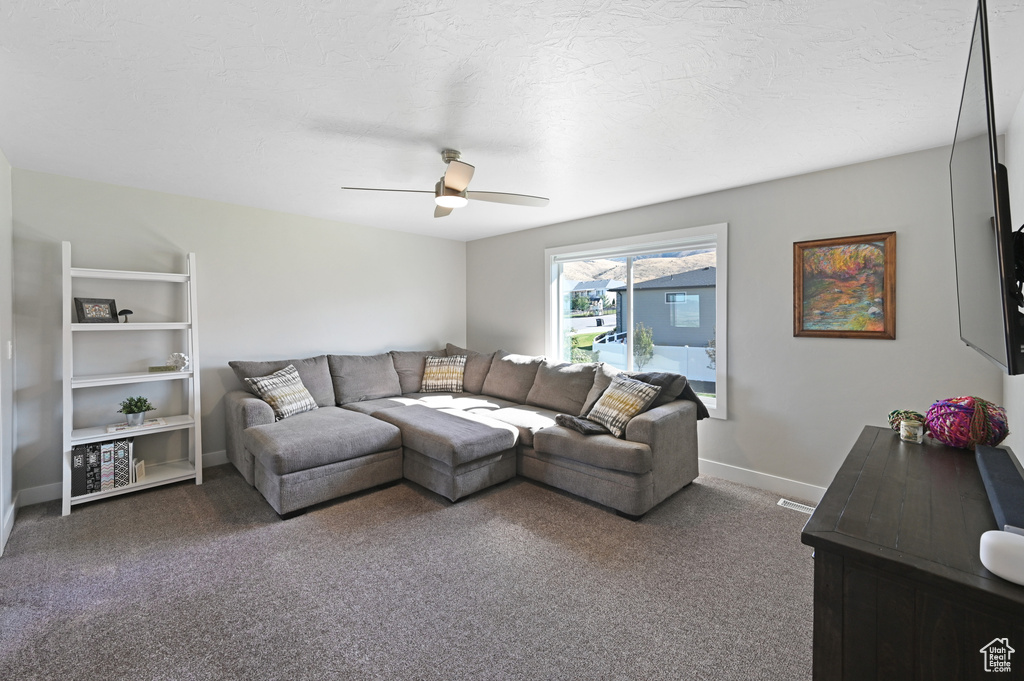 Living room featuring ceiling fan, a textured ceiling, and carpet flooring