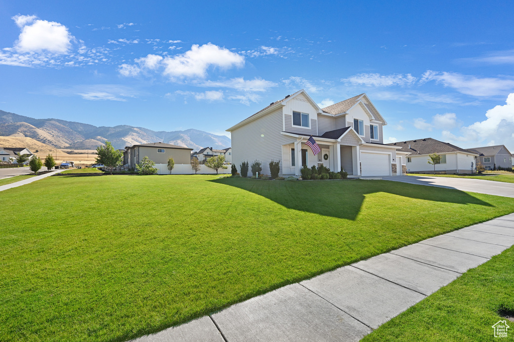 View of front of house featuring a garage, a mountain view, and a front yard