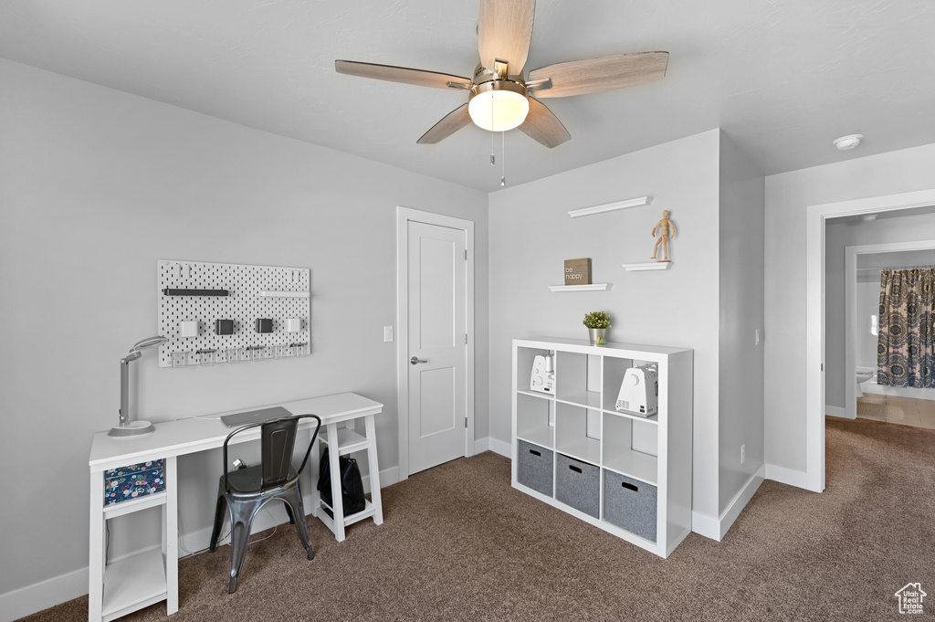 Carpeted office featuring ceiling fan