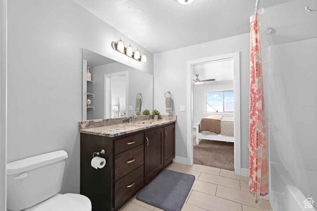 Bathroom with a shower with shower curtain, tile patterned floors, ceiling fan, vanity, and toilet