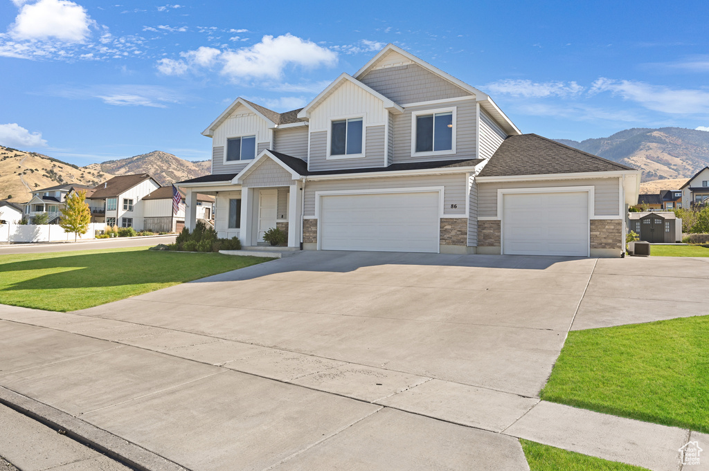 View of front of home with a mountain view, a front yard, and a garage