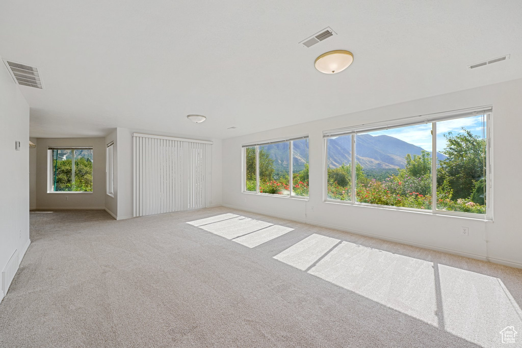 Empty room with light colored carpet and a mountain view