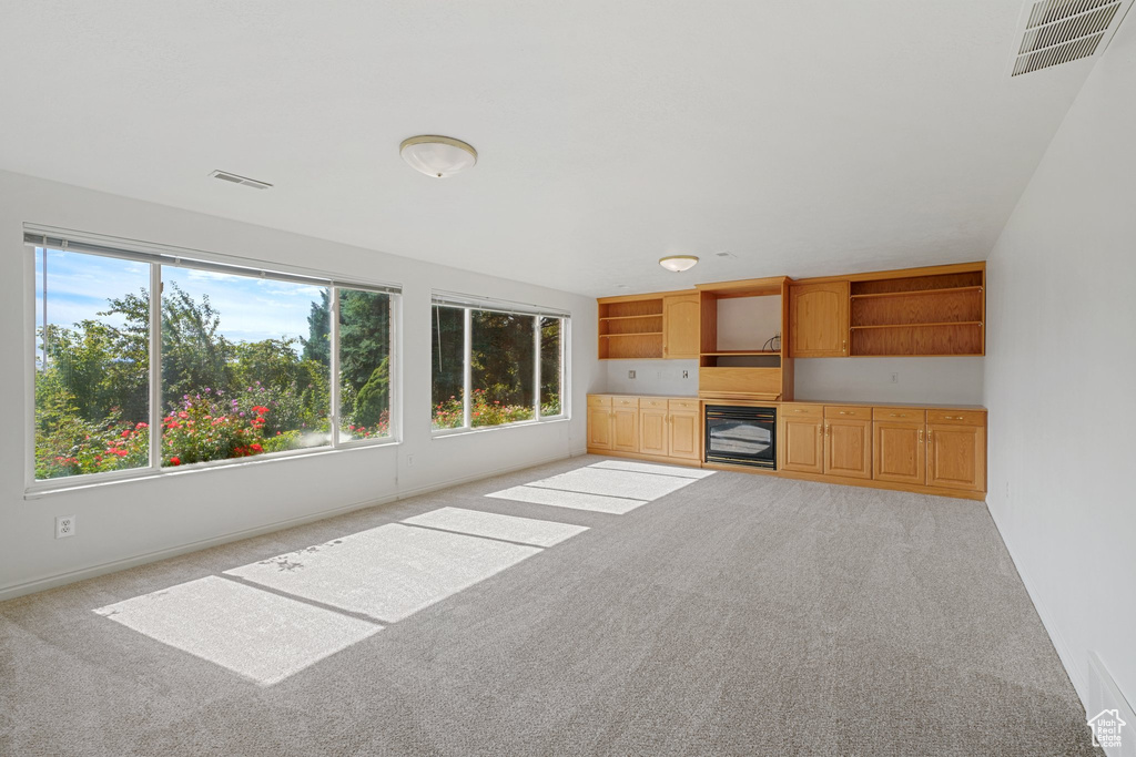 Unfurnished living room featuring light colored carpet and wine cooler