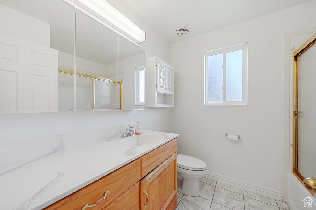 Full bathroom featuring tile patterned flooring, bath / shower combo with glass door, vanity, and toilet