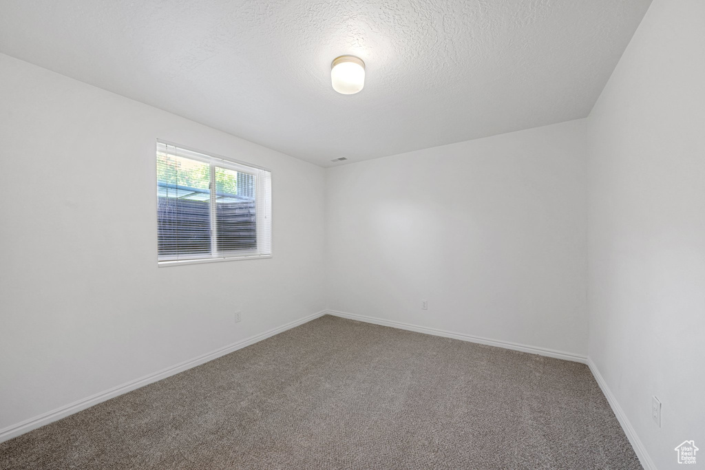 Empty room with a textured ceiling and carpet