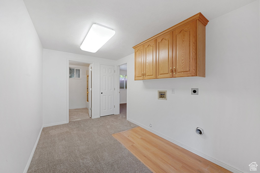 Clothes washing area featuring washer hookup, electric dryer hookup, cabinets, gas dryer hookup, and light colored carpet