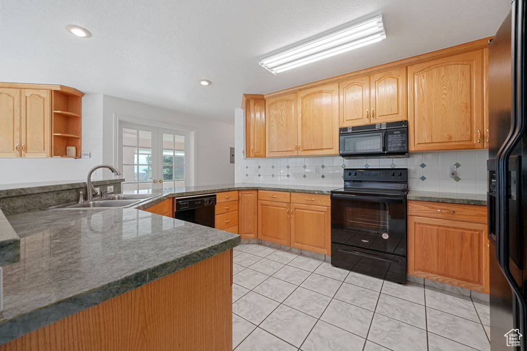 Kitchen with black appliances, light tile patterned flooring, sink, and tasteful backsplash