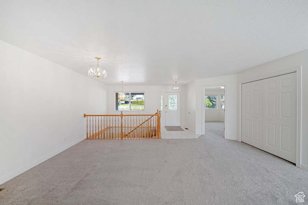 Carpeted spare room featuring a chandelier