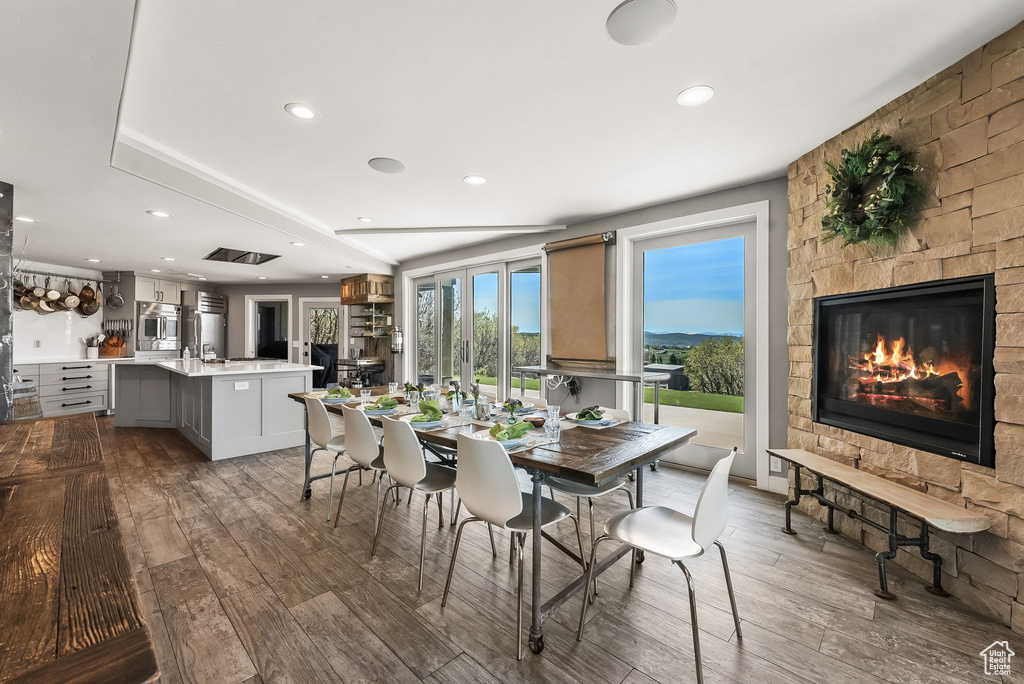 Dining space featuring wood-type flooring and a stone fireplace