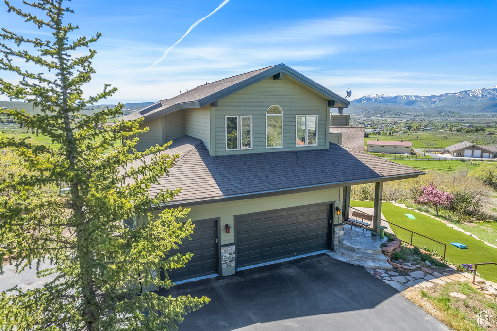 View of front of property with a mountain view, a front lawn, and a garage