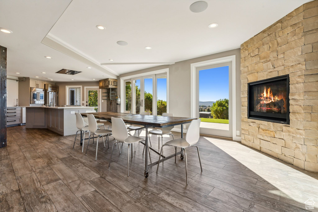 Dining area with a stone fireplace and hardwood / wood-style floors