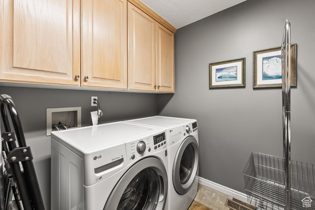 Laundry room featuring cabinets, tile patterned flooring, washer and dryer, and a textured ceiling