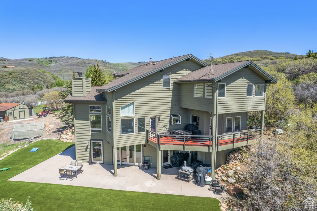 Rear view of house with a lawn, a patio, a deck with mountain view, and a shed