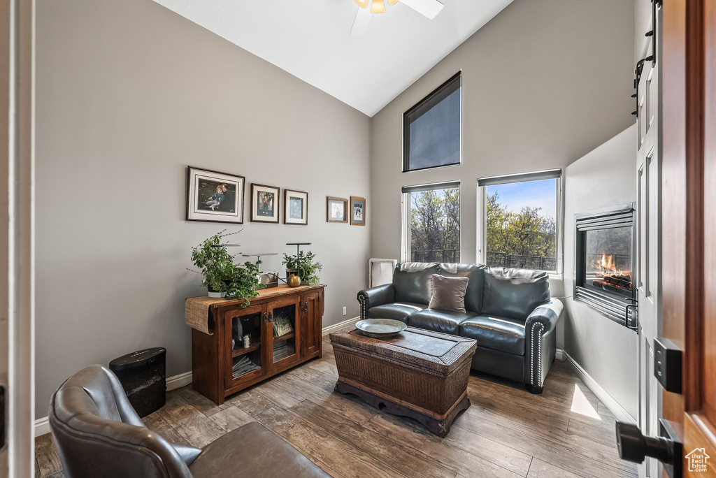 Living room with hardwood / wood-style floors, ceiling fan, and high vaulted ceiling