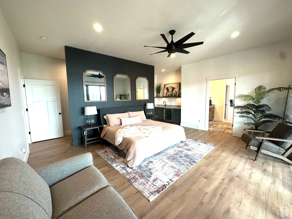 Bedroom with connected bathroom, light hardwood / wood-style floors, and ceiling fan