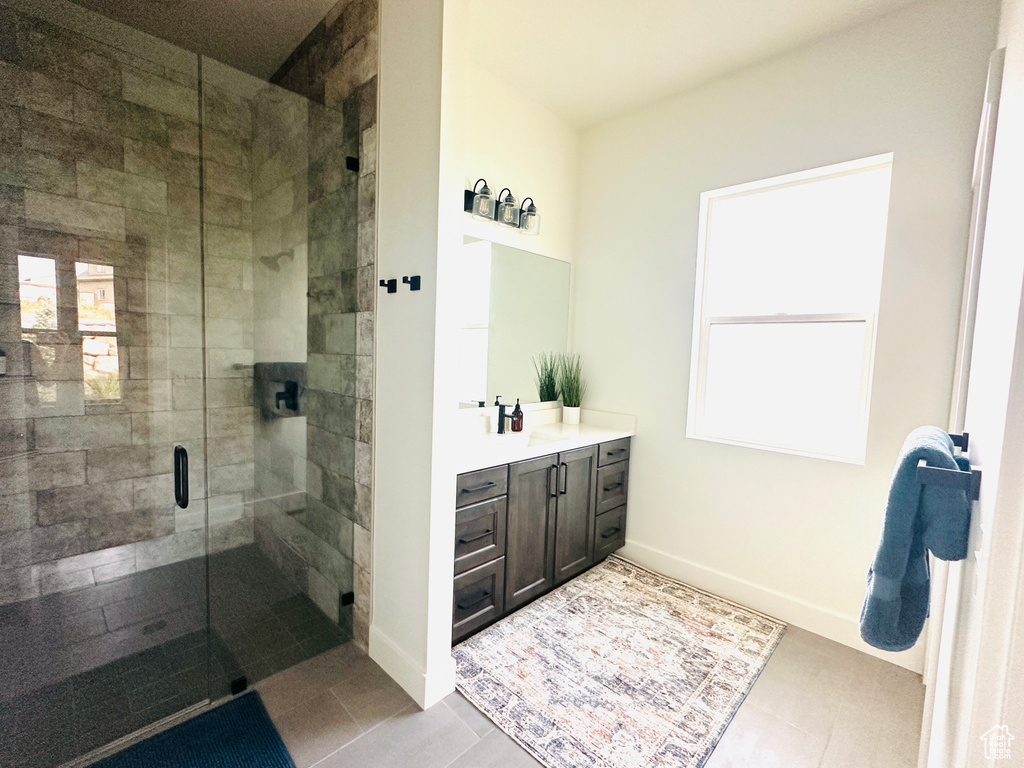 Bathroom featuring tile patterned floors, a shower with door, and vanity