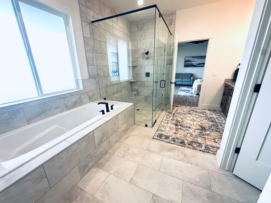 Bathroom featuring shower with separate bathtub and vanity