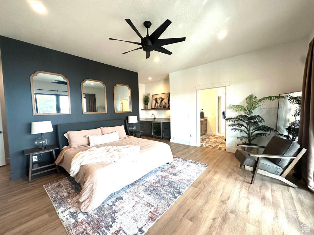 Bedroom featuring light wood-type flooring, ensuite bath, ceiling fan, and sink