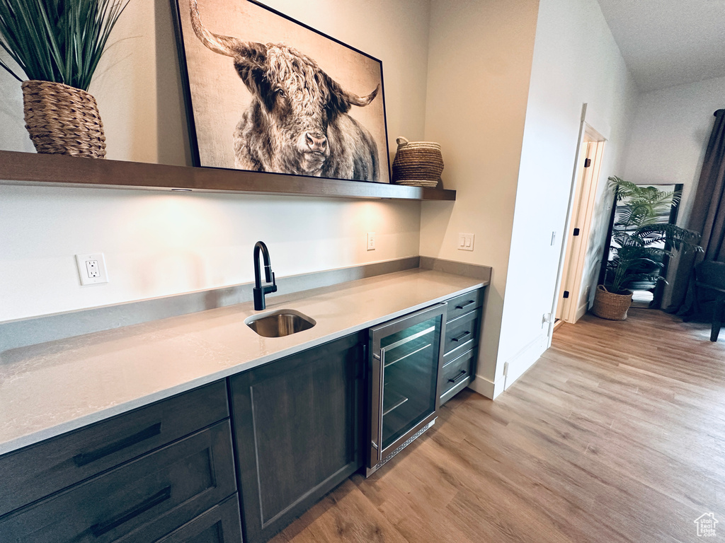 Bar featuring beverage cooler, light hardwood / wood-style flooring, and sink