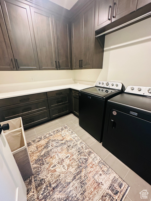 Laundry room with cabinets, independent washer and dryer, and light tile patterned flooring