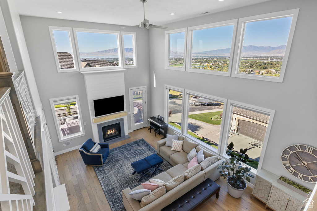 Living room with a healthy amount of sunlight, a towering ceiling, ceiling fan, and light hardwood / wood-style flooring