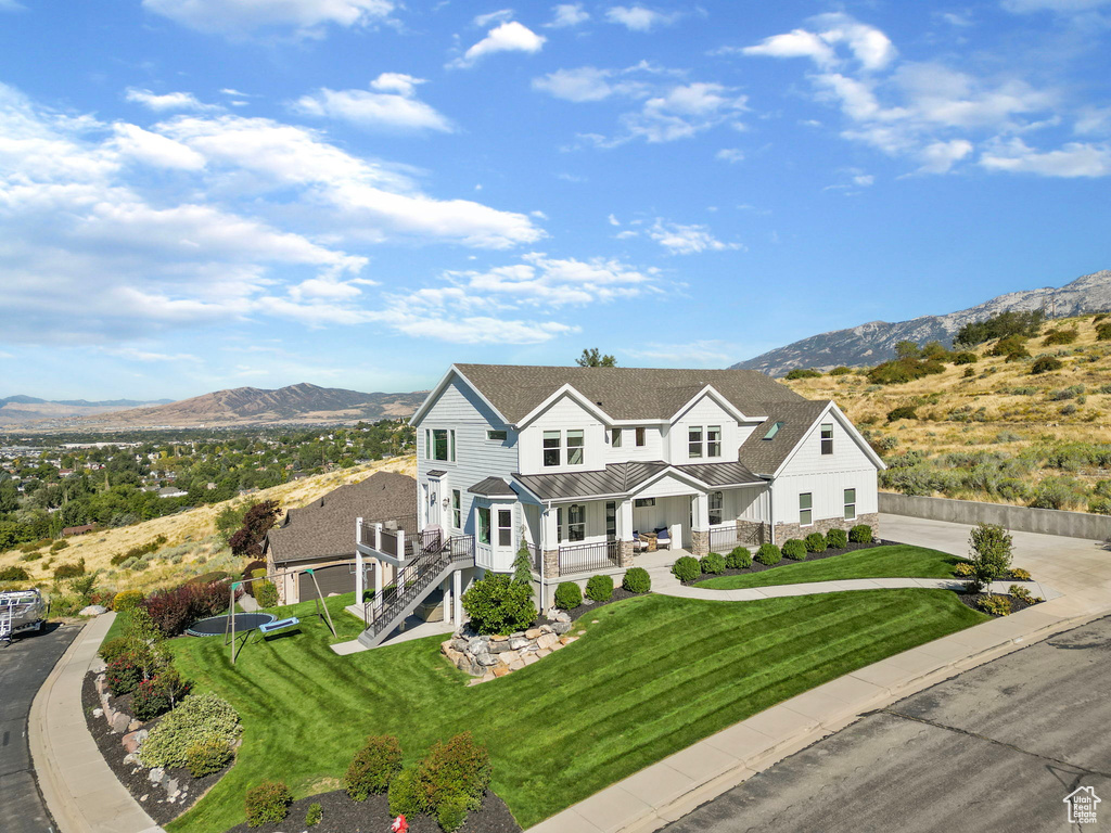 View of front of property featuring a front yard, a mountain view, and a porch