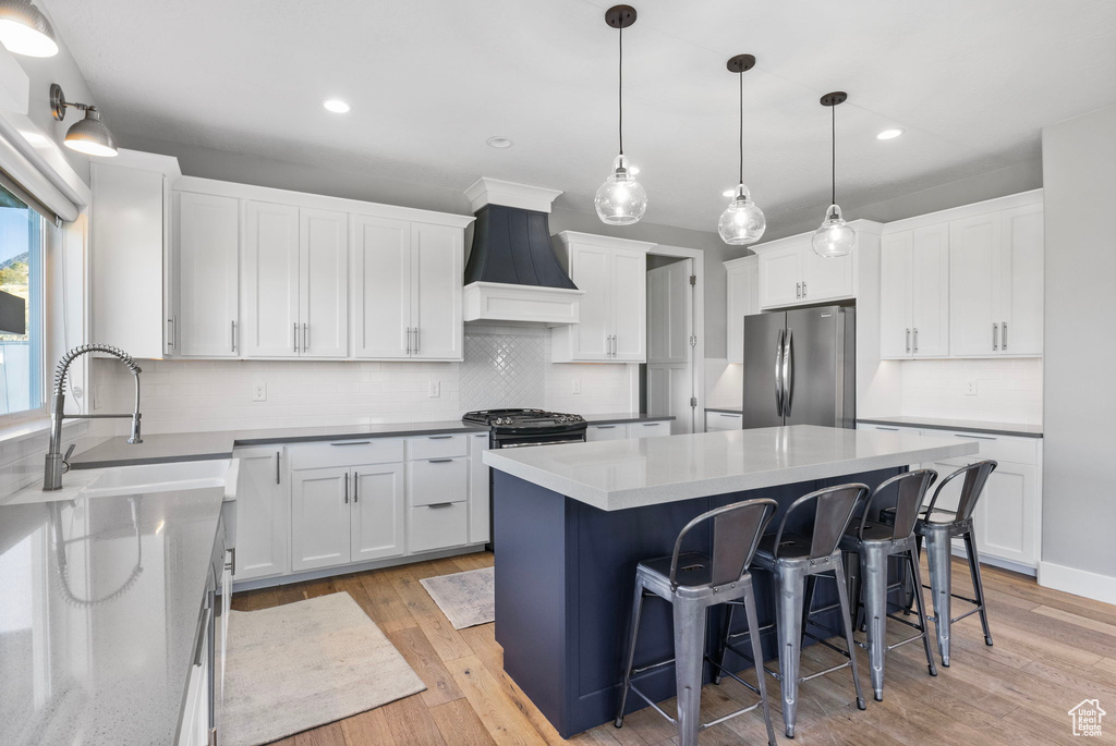 Kitchen with stainless steel fridge, premium range hood, and white cabinetry